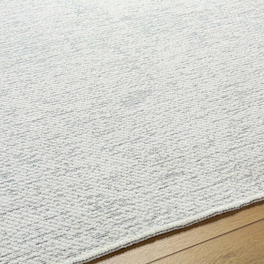 Close-up of the Isako Cream & Gray Solid Washable Area Rug showing its subtle pattern and soft, textured weave. Texture