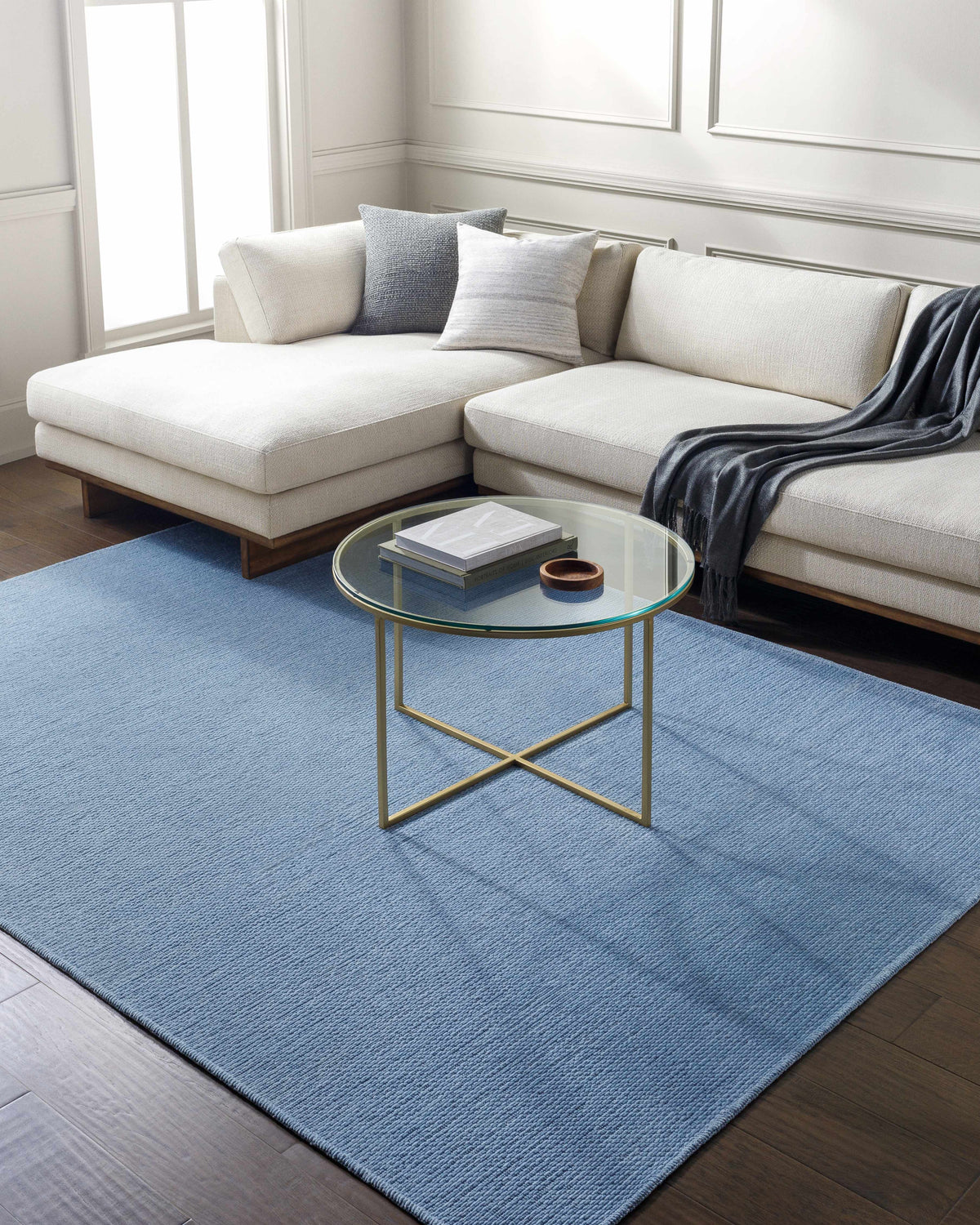 Living room with light blue Isako Blue Solid Washable Area Rug, white sectional sofa, and round glass coffee table. Roomscene-Rectangle