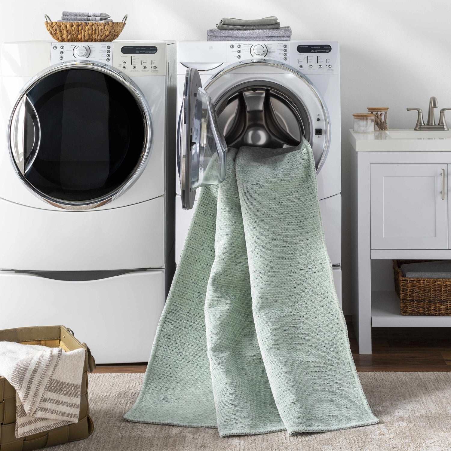 Laundry room scene with Isako Seafoam Solid Washable Area Rug coming out of the washing machine. White washer and dryer. Washing-Machine