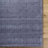 Close-up of the Sanvi Charcoal Area Rug. Hand-tufted wool rug with a contemporary grid pattern in black and charcoal. Corner