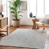 Living room scene with a gray Aiman Area Rug, wood floors, and a modern chair and cabinet. Roomscene-Rectangle