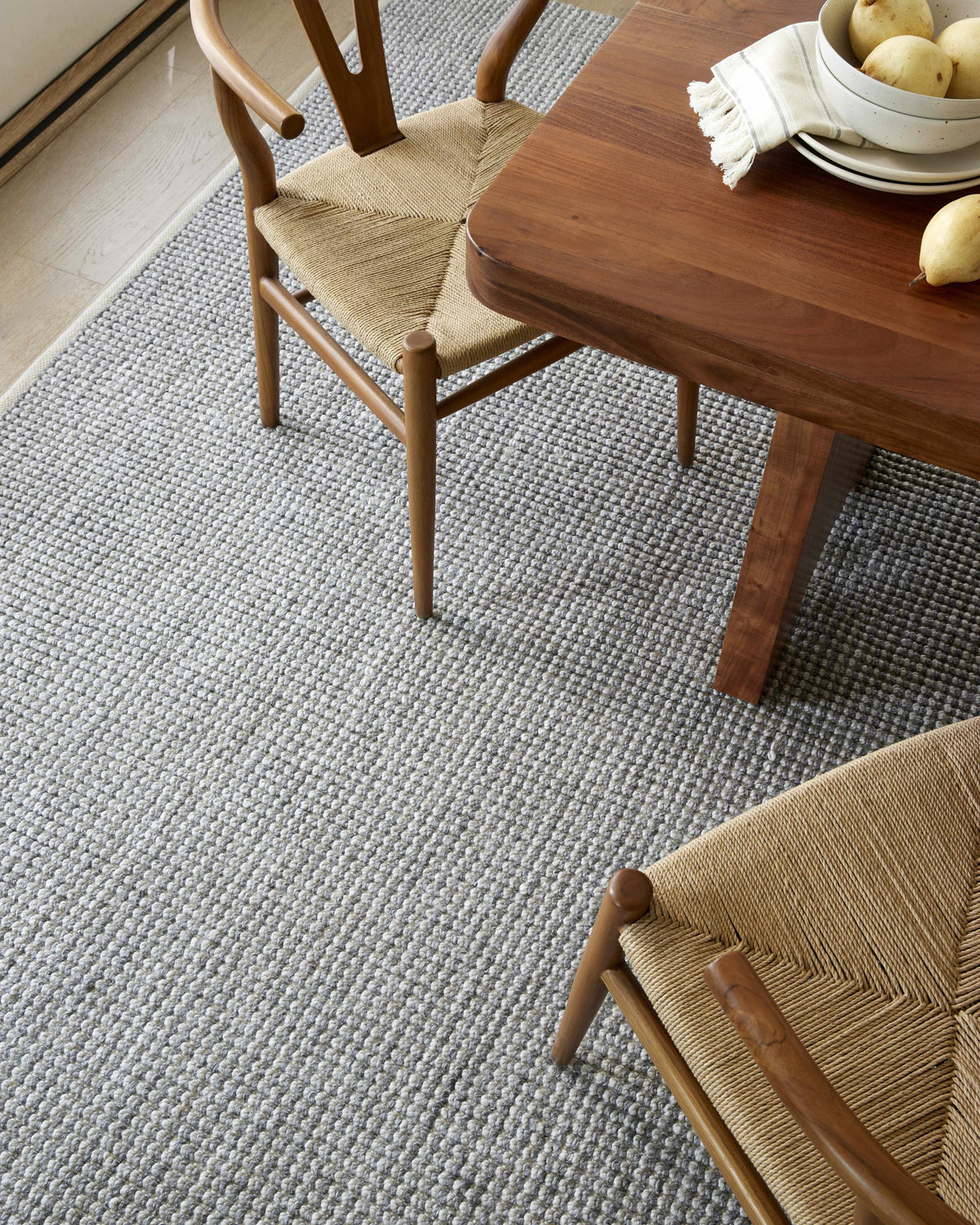 Dining room scene with wood table and chairs on a gray Aiman Area Rug. Styleshot
