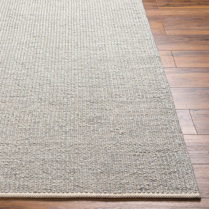 Close-up of the hand-woven Blaga Area Rug in cloud gray and lambswool on a wood floor. Contemporary style. Front