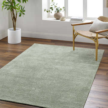 Light sage Helio Area Rug in a bright living room with wood floors and a woven chair. Roomscene-Rectangle