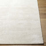 Close-up of the hand-tufted Nazih Area Rug. Light silver and off-white viscose rug with subtle horizontal texture. Front