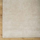 Close-up of the Pearl Pirro Premium Wool Blend Rug, showing its subtle texture and neutral color on wood flooring. Corner