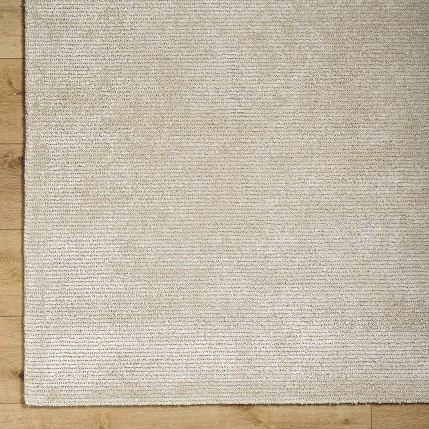 Close-up of the Pearl Pirro Premium Wool Blend Rug, showing its subtle texture and neutral color on wood flooring. Corner