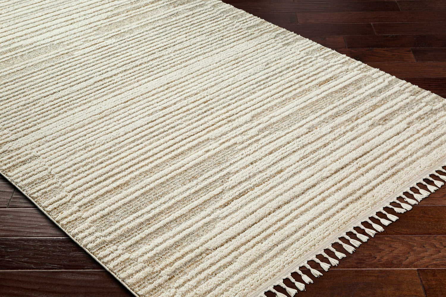 Close up of the Levy Beige Area Rug showing its striped pattern, tassels, and soft texture on dark wood floors. Corner