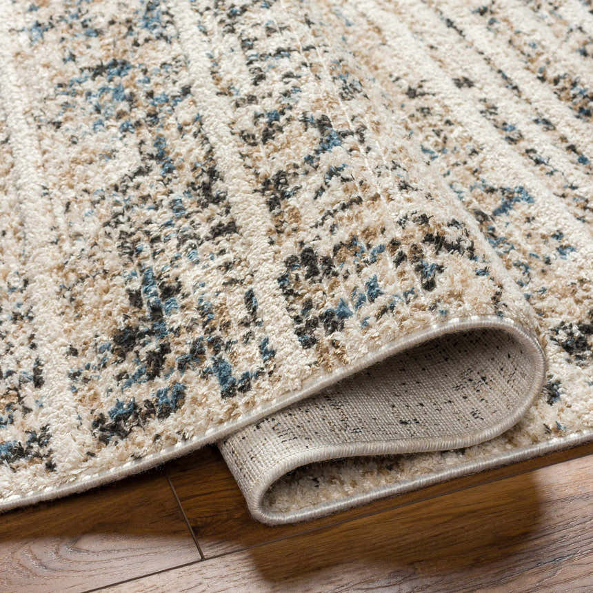 Close-up of the Miyu Brown Area Rug showing beige, brown, and blue abstract pattern and woven texture. Fold