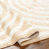 Close-up of the Arnel Beige Area Rug showing the bone and light brown geometric shag design and machine-woven construction. Fold