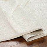 Close-up of the Horst Off White Area Rug showing its plush, shag texture and durable backing on a wood floor. Fold