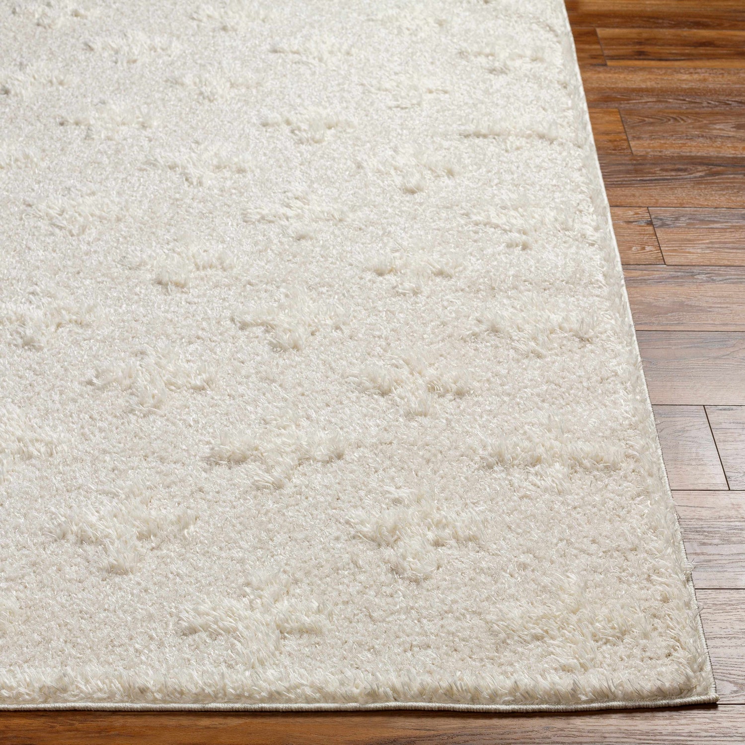 Close-up of the Satu Cream Area Rug showing its shag texture and subtle geometric pattern on wood flooring. Front