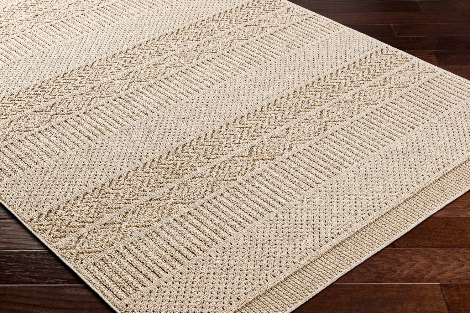 Close-up of the Corom Beige Area Rug showing its textured, geometric pattern and neutral color on dark wood floors. Corner
