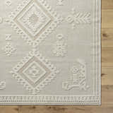 Close-up of the Galam Area Rug in khaki and tan, featuring a contemporary diamond and floral pattern on a textured weave. Corner