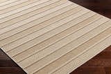Close-up of the beige Idana Area Rug showing its textured, striped, machine-woven design on dark wood floors. Corner