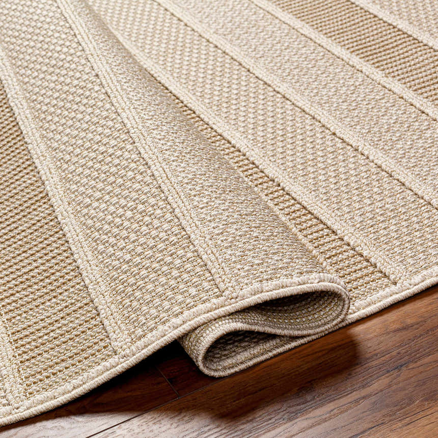 Close-up of the beige and brown Idana Area Rug showing its textured, machine-woven construction and rolled edge. Fold