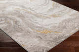 Close-up of Akins Beige Marble Rug on dark wood floor. Abstract pattern with beige, gray, and gold accents. Clearance rug. Corner