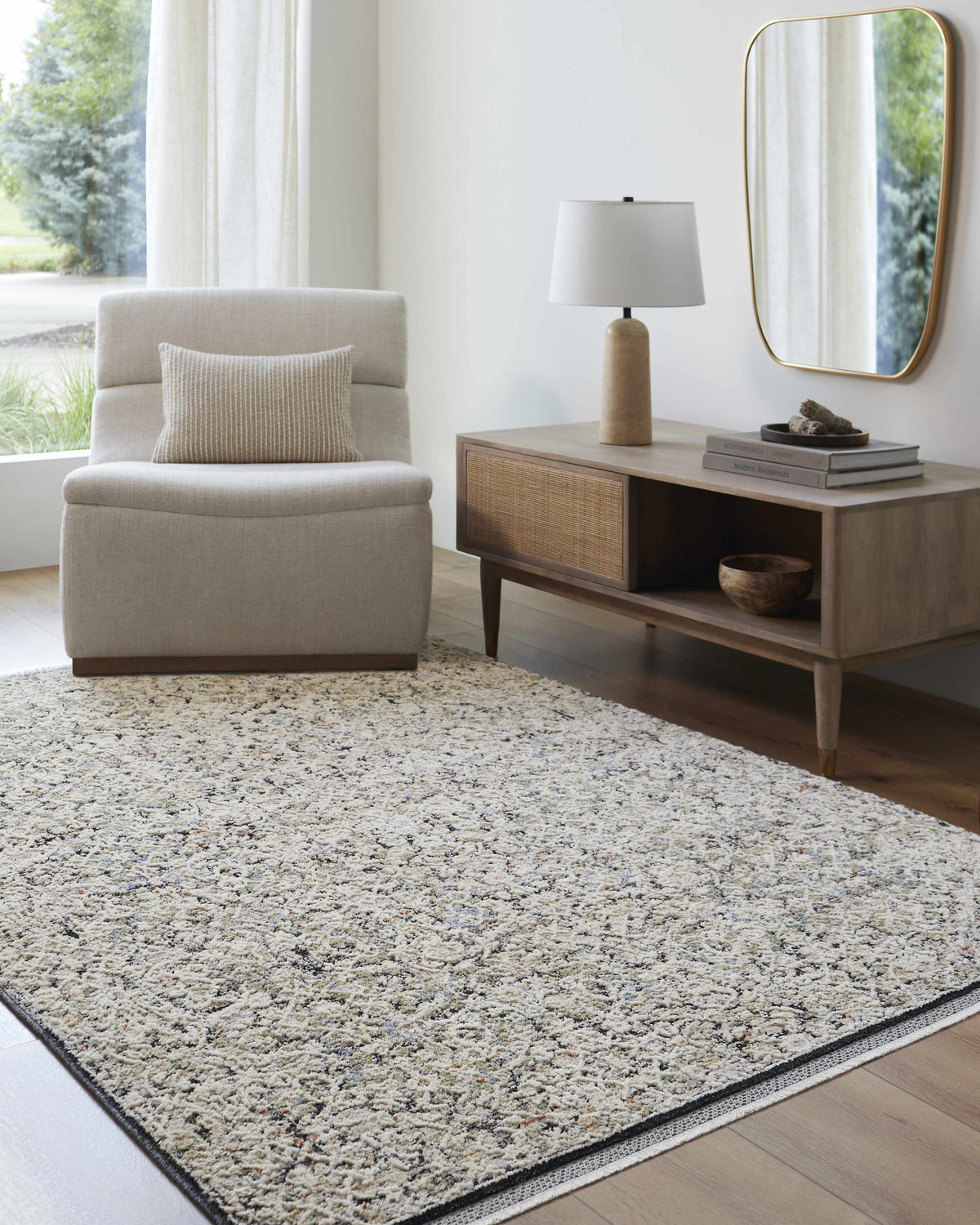 Neutral living room with a Haran Cloud Gray Area Rug, chair, wood console table, and gold mirror. Roomscene-Rectangle