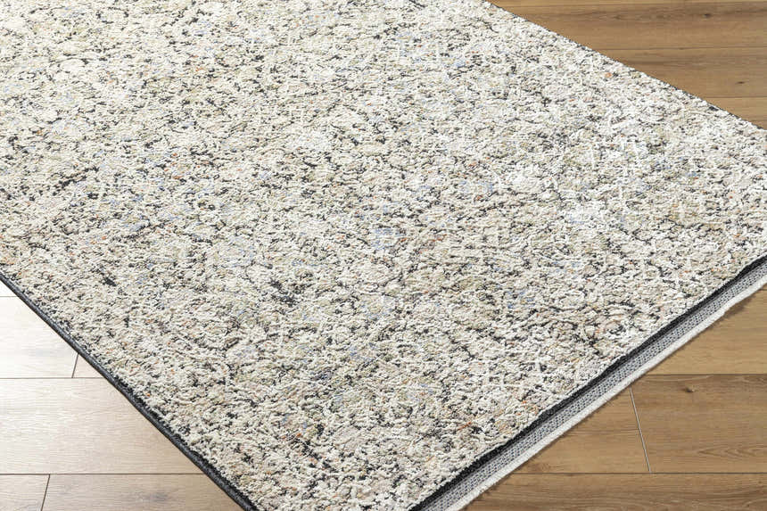 Close-up of the Haran Cloud Gray Area Rug showing its textured, neutral-toned design on hardwood flooring. Corner