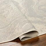 Close-up of the Basma Cream Marble Area Rug showing beige and gray tones and subtle marble pattern. Fold