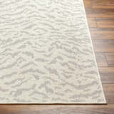 Close-up of Friso Cream Area Rug showing beige and gray contemporary pattern and woven texture on wood floor. Front
