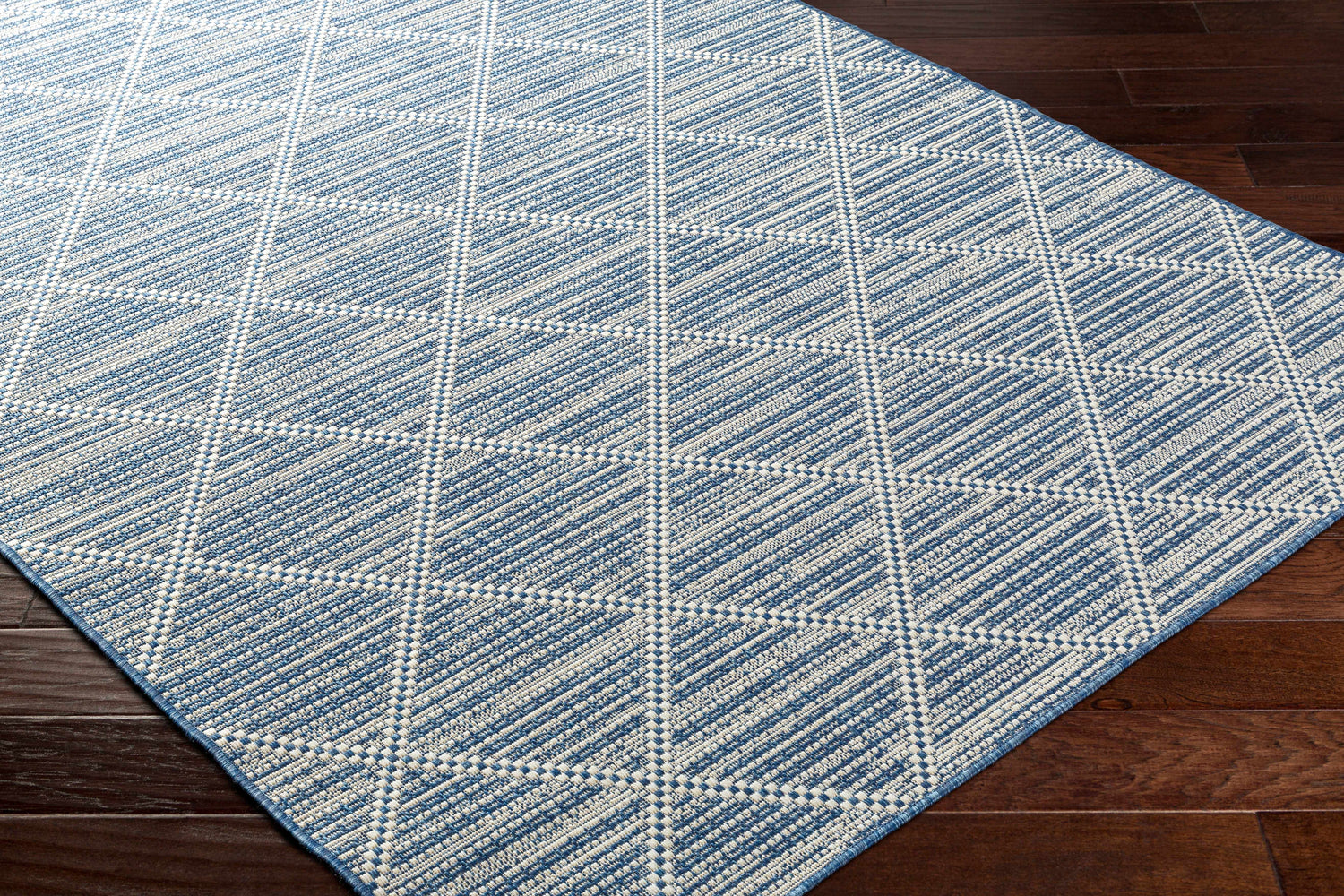 Close-up of the Ivora Blue Area Rug showing its textured, geometric diamond pattern in denim and white. Corner