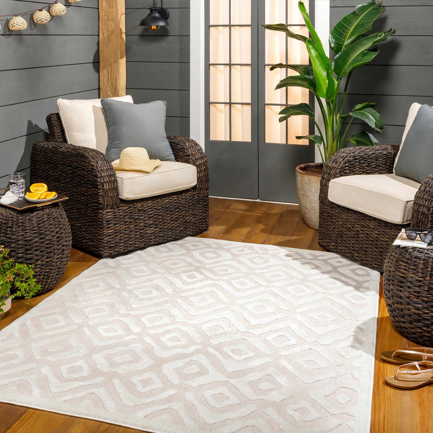 Cozy outdoor patio with wicker furniture and Burl Cream Outdoor Rug. Roomscene-Rectangle