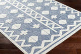 Close-up of Elio Blue Outdoor Rug showing its denim blue color and geometric white pattern. Corner