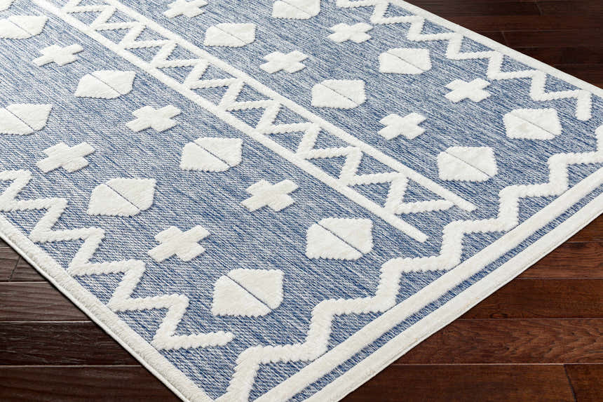 Close-up of Elio Blue Outdoor Rug showing its denim blue color and geometric white pattern. Corner