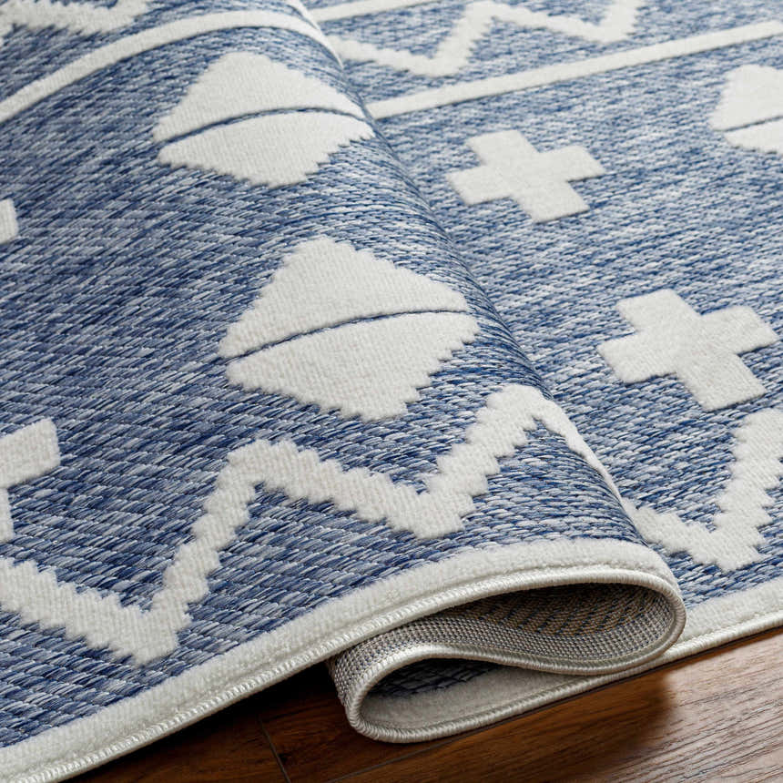 Close up of the Elio Blue Outdoor Rug featuring a geometric pattern in denim and white. Fold
