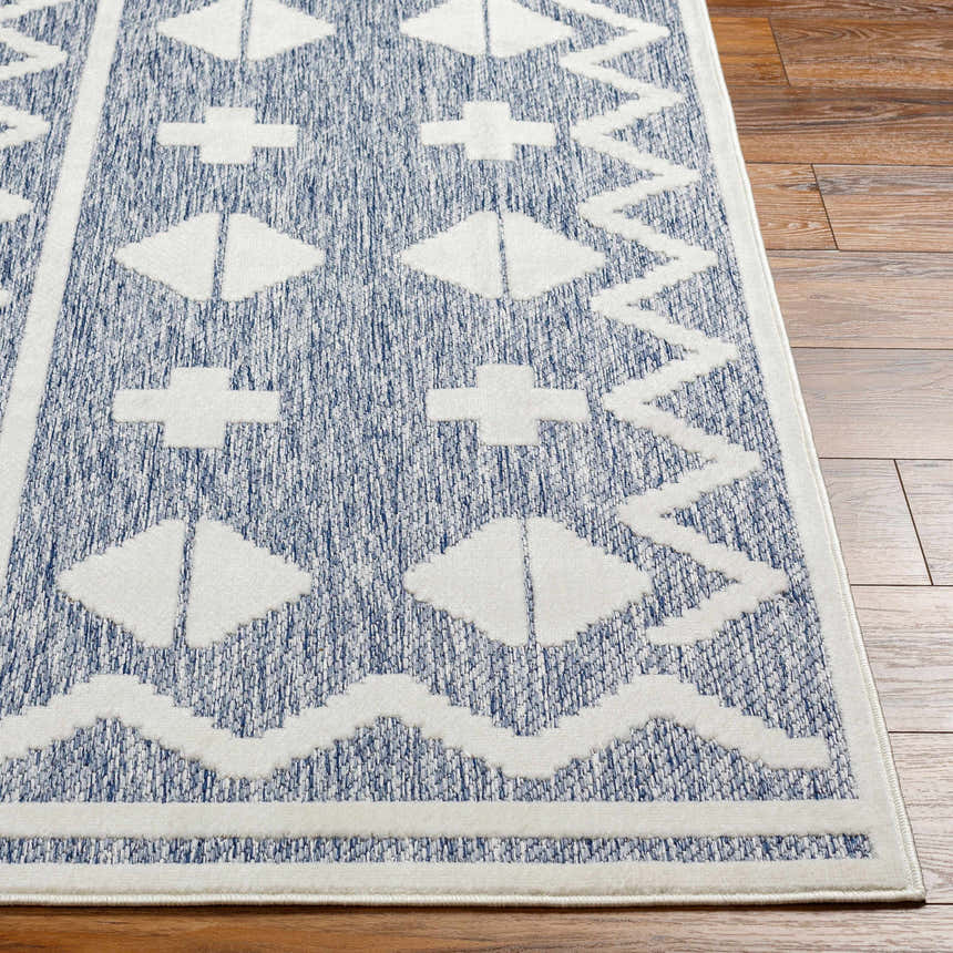 Close-up of Elio Blue Outdoor Rug showing the denim and white geometric pattern and texture on wood flooring. Front