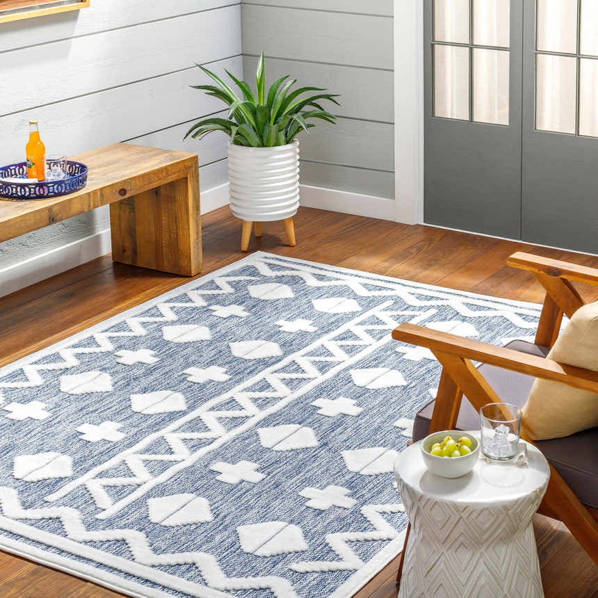 Cozy sunroom with Elio Blue Outdoor Rug, wood floors, bench, chair, and potted plant. Contemporary style. Roomscene-Rectangle