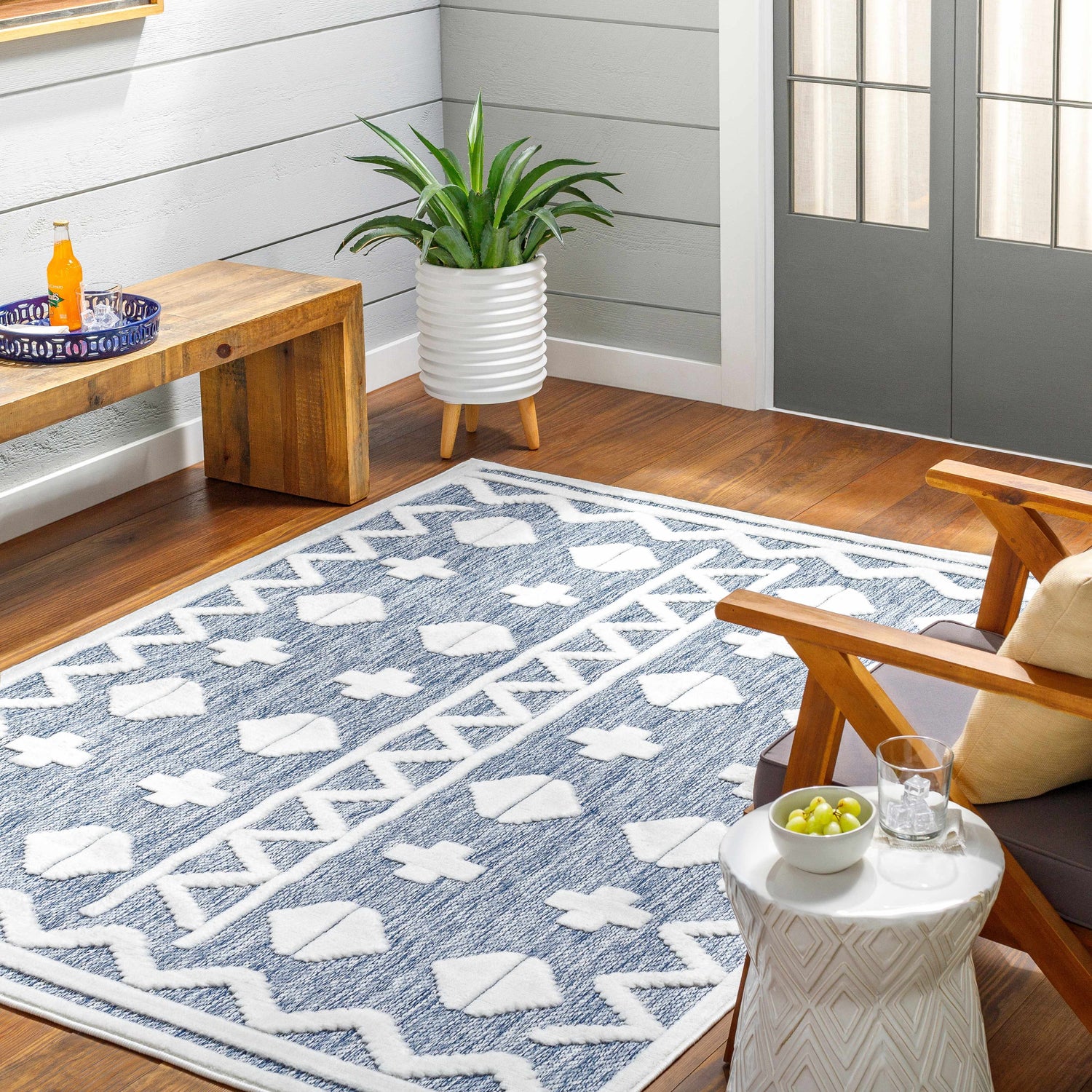 Cozy sunroom with Elio Blue Outdoor Rug, wood floors, bench, chair, and potted plant. Contemporary style. Roomscene-Rectangle