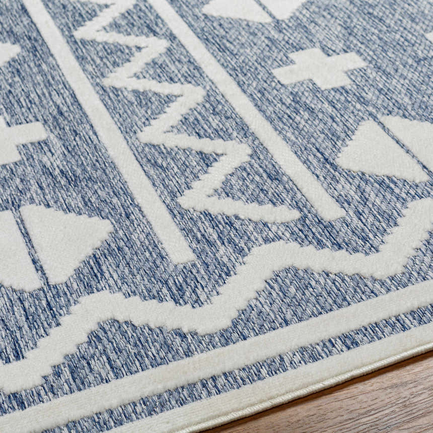 Close-up of Elio Blue Outdoor Rug showing geometric white pattern on denim blue textured weave. Texture