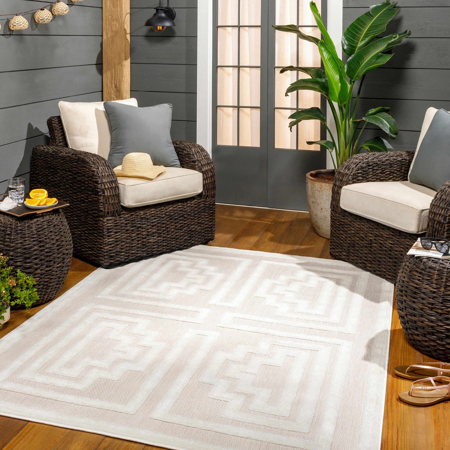 Cozy outdoor patio scene with wicker furniture and the Yves Cream Outdoor Rug. Roomscene-Rectangle