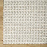 Close-up of the Lenci Hand Woven Wool Area Rug, showcasing beige and rose cream colors and braided texture on wood floor. Corner