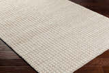 Close up of the Lenci Hand Woven Wool Area Rug, showing its beige and rose cream color and textured, hand woven design. Corner