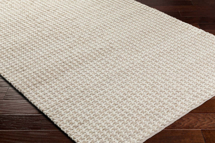 Close up of the Lenci Hand Woven Wool Area Rug, showing its beige and rose cream color and textured, hand woven design. Corner