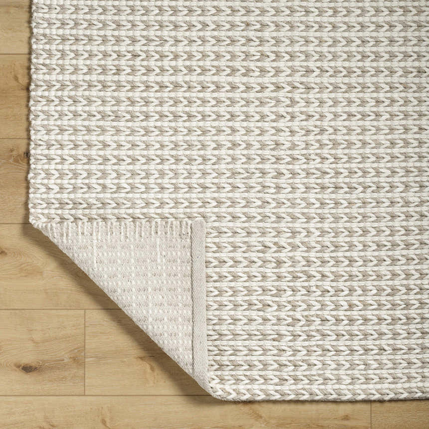 Close-up of the hand woven Lenci Wool Area Rug in beige and rose cream with a braided texture. Fold