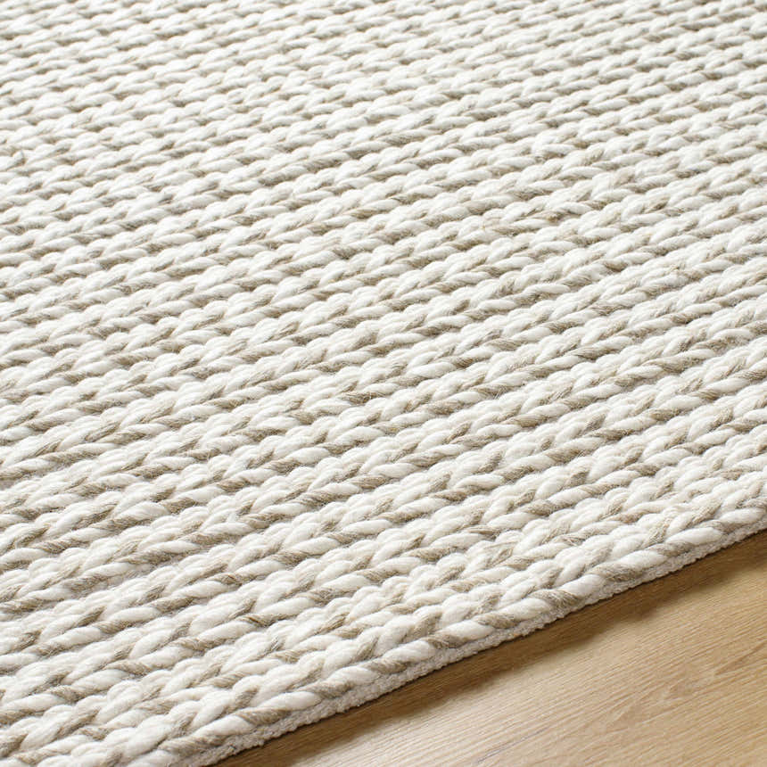 Close up of the Lenci Hand Woven Wool Area Rug showing beige and rose cream braided texture on wood floor. Texture