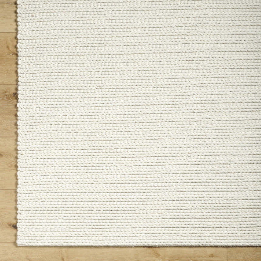 Close up of the hand woven Lenci Rose Cream Area Rug showing beige, ivory, and cream colors and wool texture. Corner