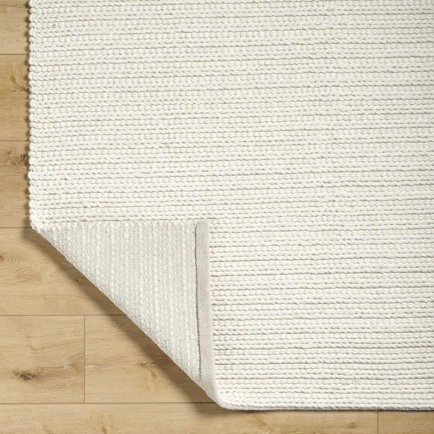 Close-up of the hand woven Lenci Rose Cream Area Rug showing its beige, ivory, and rose cream colors and textured design. Fold