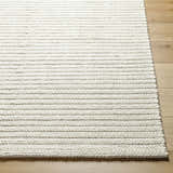 Close-up of Lenci Rose Cream area rug showing woven texture and beige color on light wood floor. Front