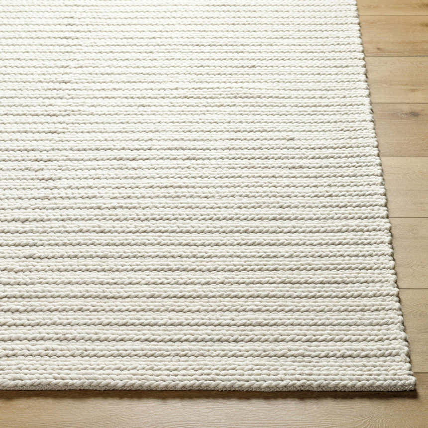 Close-up of Lenci Rose Cream area rug showing woven texture and beige color on light wood floor. Front