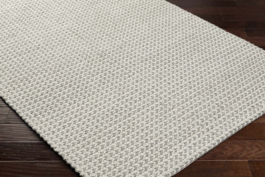 Close-up of the hand woven Lenci Bone Area Rug showing beige and bone colors and textured wool and cotton blend. Corner