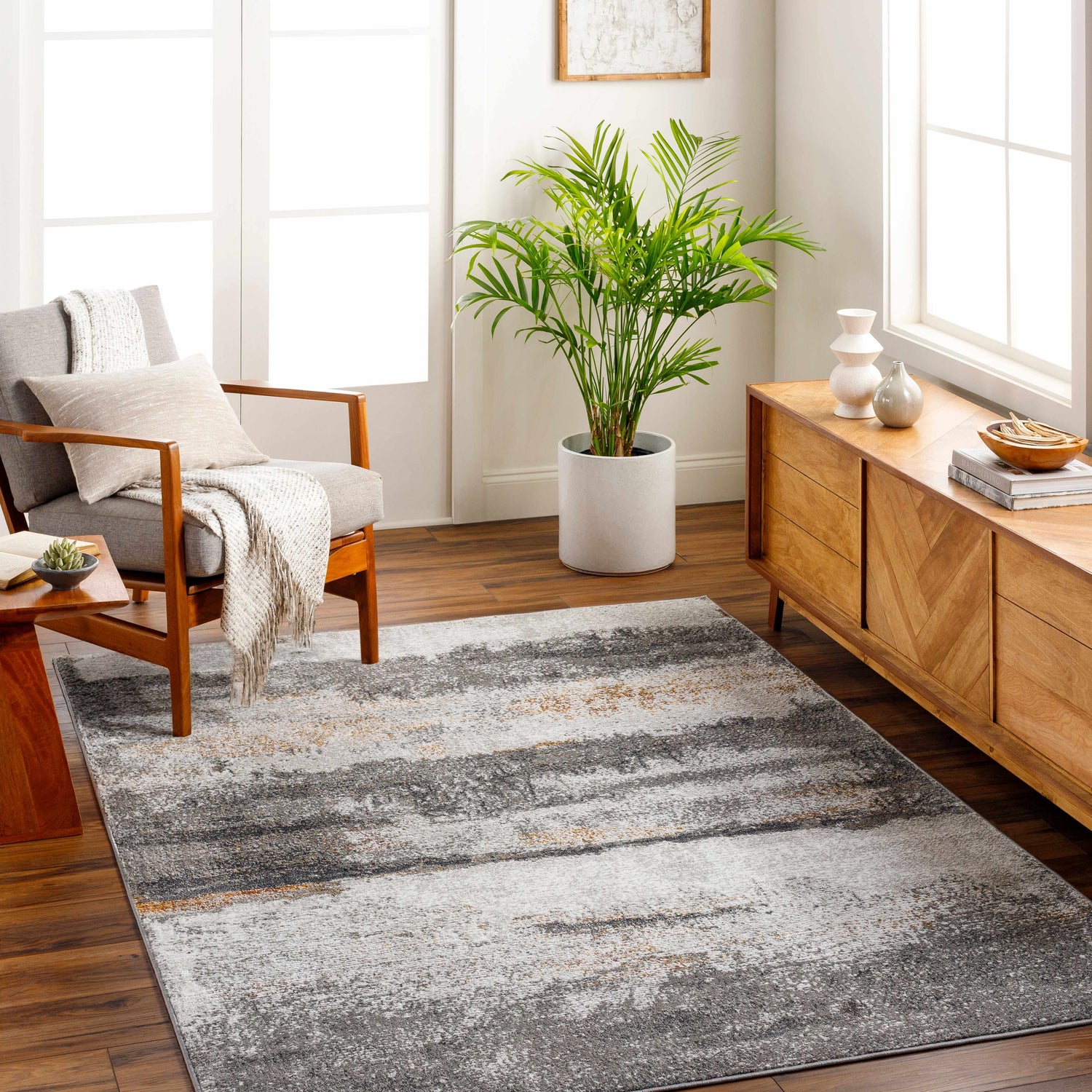 Living room scene with gray armchair and Adam Gray Abstract Area Rug in charcoal, brown, and gray tones. Roomscene-Rectangle