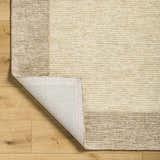Close-up of the Amadi Area Rug showing its tan and pearl colors, wool texture, and hand-tufted construction. Fold