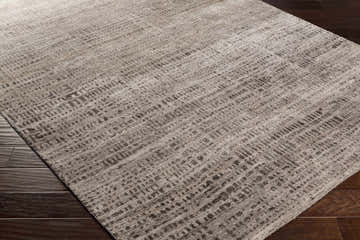 Close up of the Stanley Area Carpet showing its subtle geometric pattern and soft texture on dark wood floors. Corner