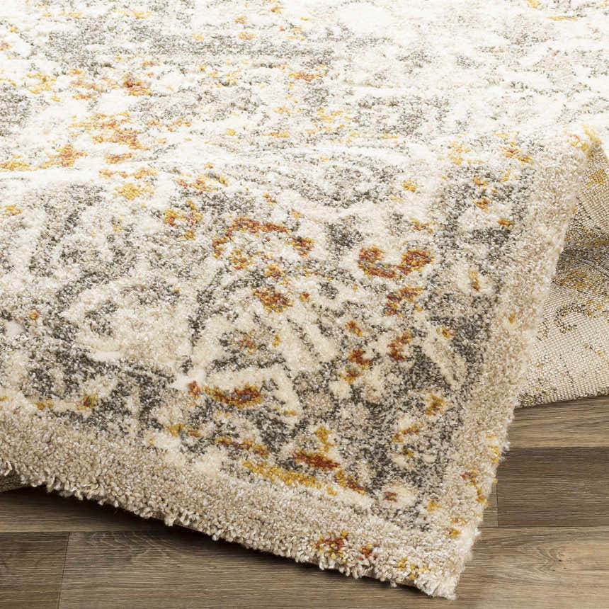 Close-up of the Stockwell Thick Luxe Rug. Features a vintage-inspired pattern in ivory, gold, brown, and gray hues. Soft, textured pile. Fold