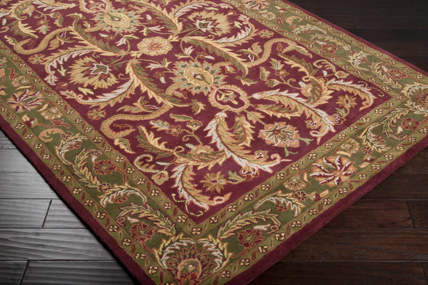Close-up of the Steuben Premium Wool Area Carpet in burgundy, gold, and green floral pattern on dark wood flooring. Corner